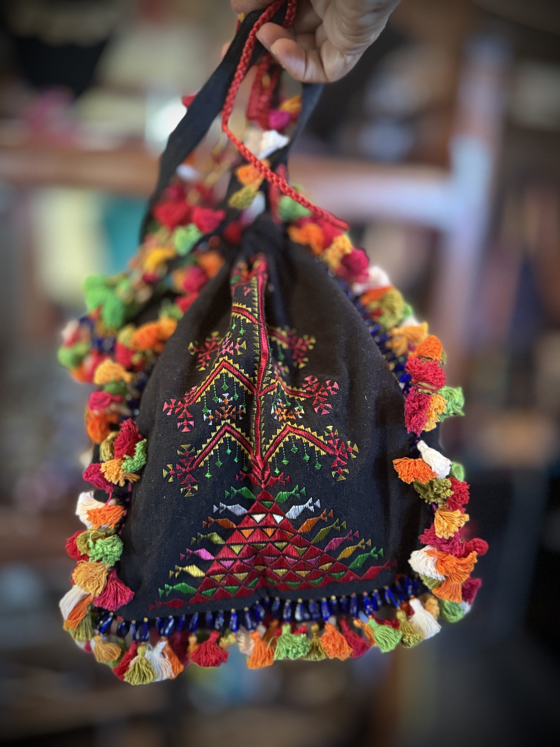 Black three-sided potli jhola with multicolored hand embroidery and tassels