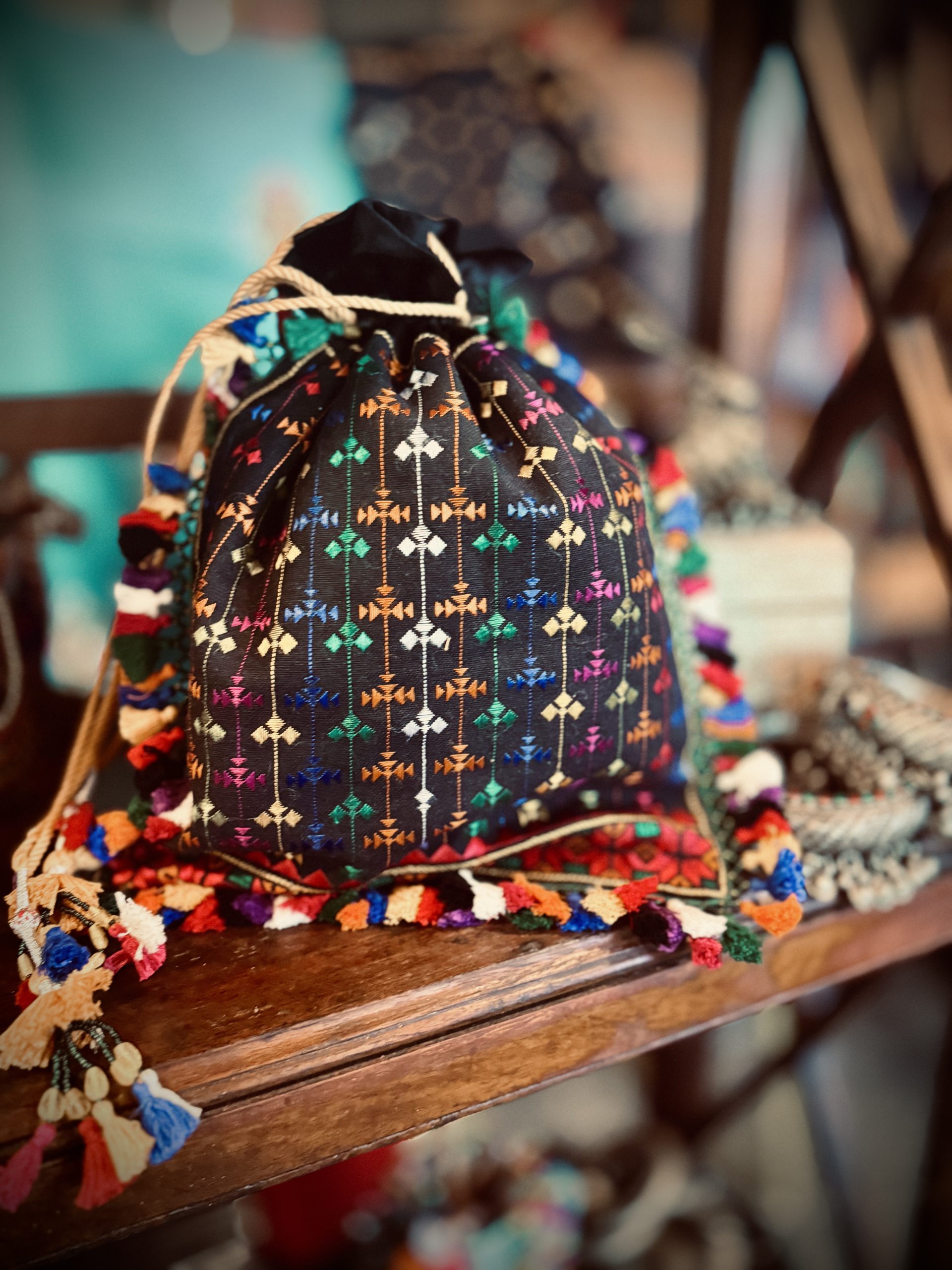Two-sided black suede potli with multicolored hand embroidery and tassels