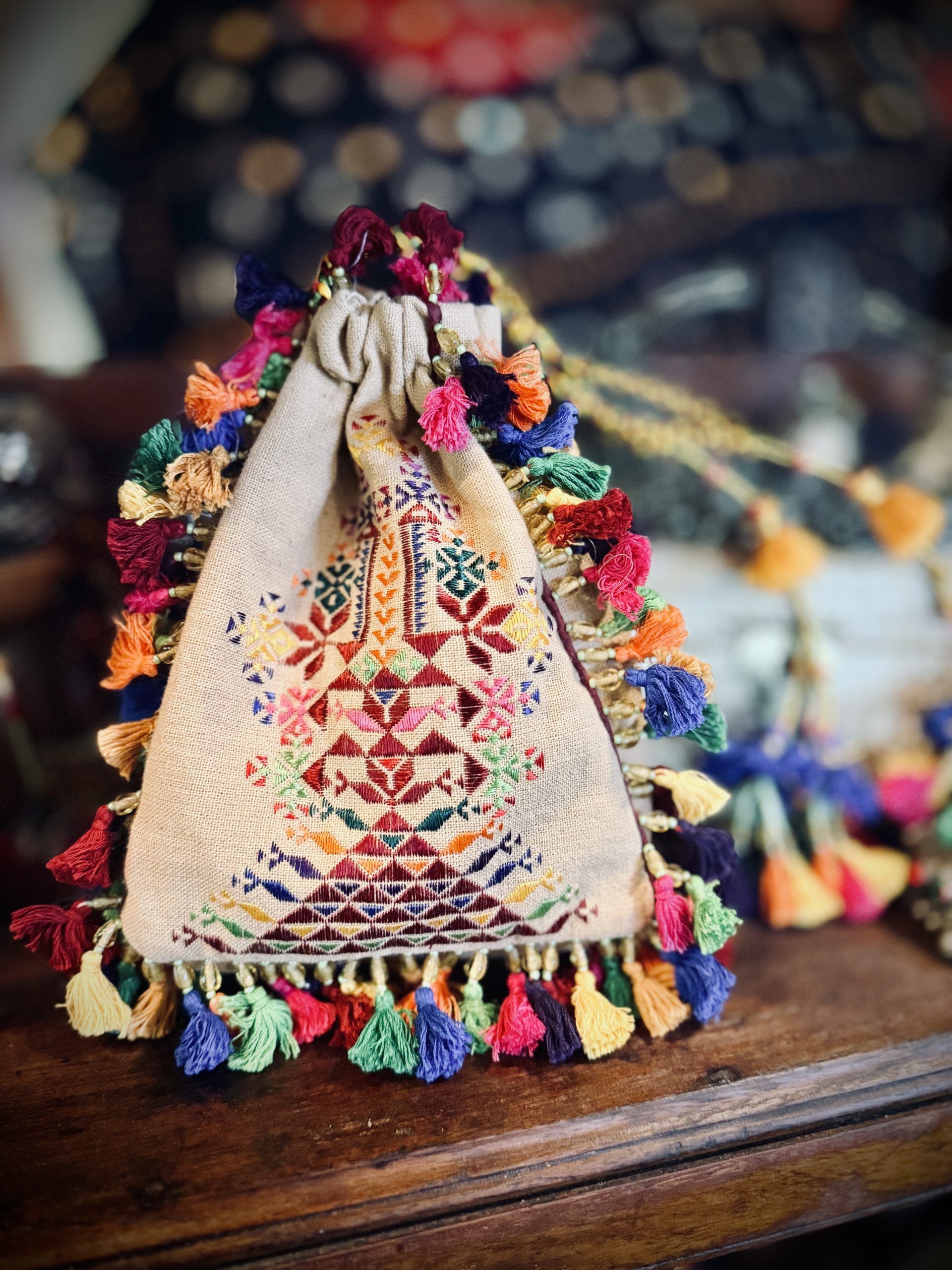 Three-sided beige cotton potli with multicolored hand embroidery and tassels