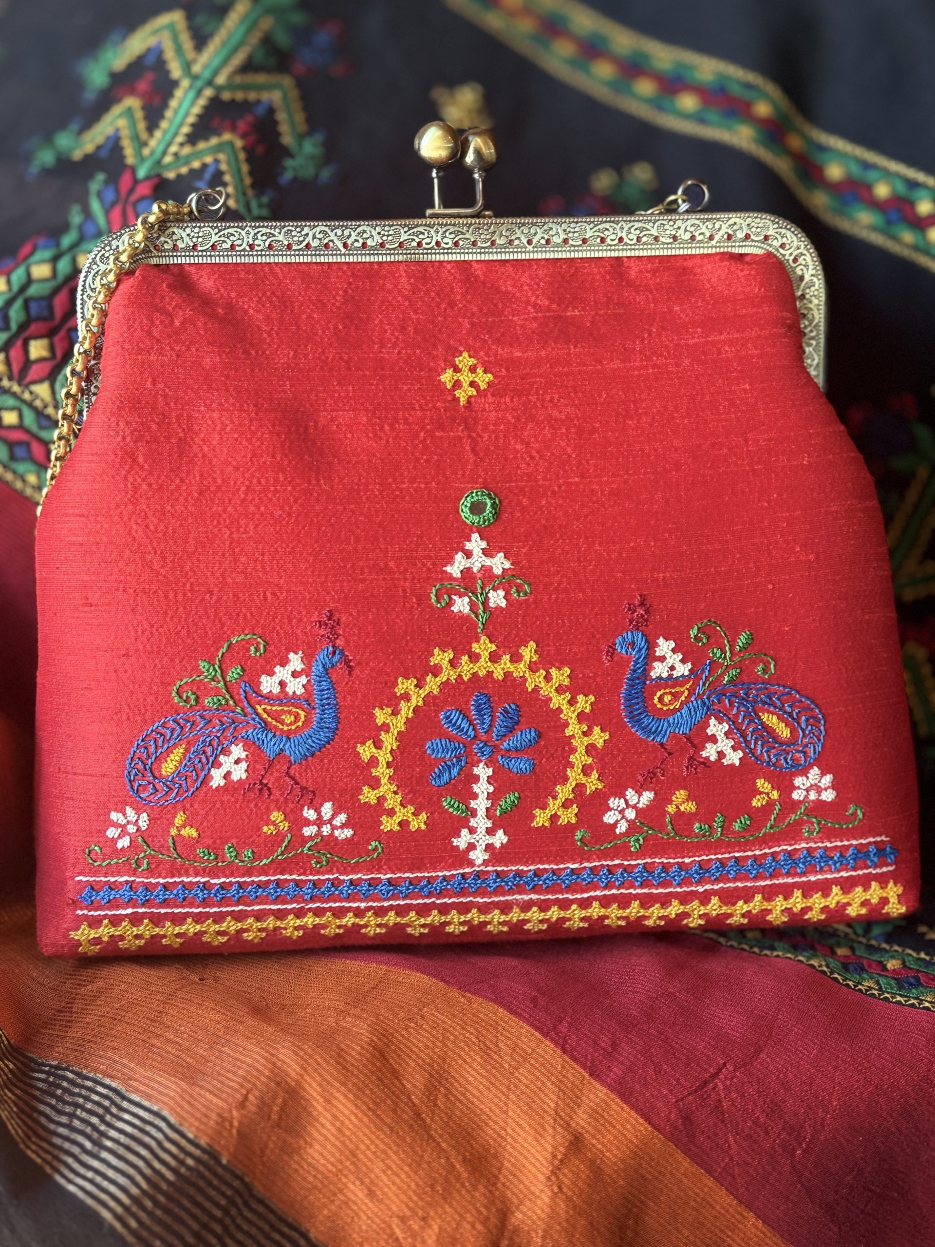 Red raw-silk handbag with hand-embroidered Kutchi peacock motifs