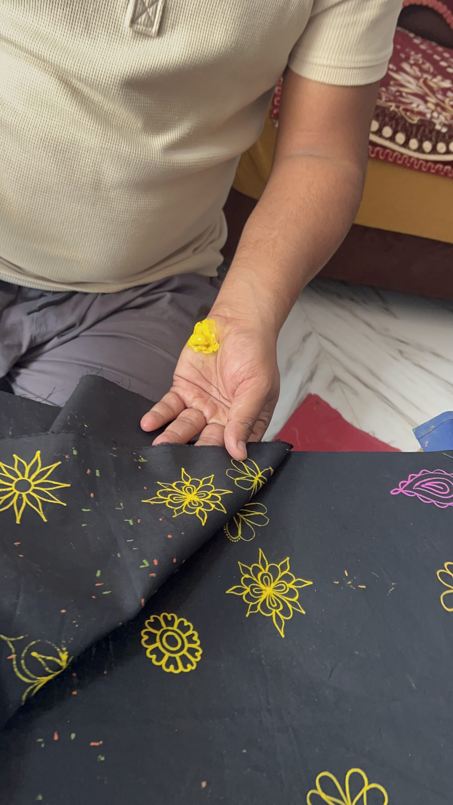 A yellow embroidered flower motif being shown by hand