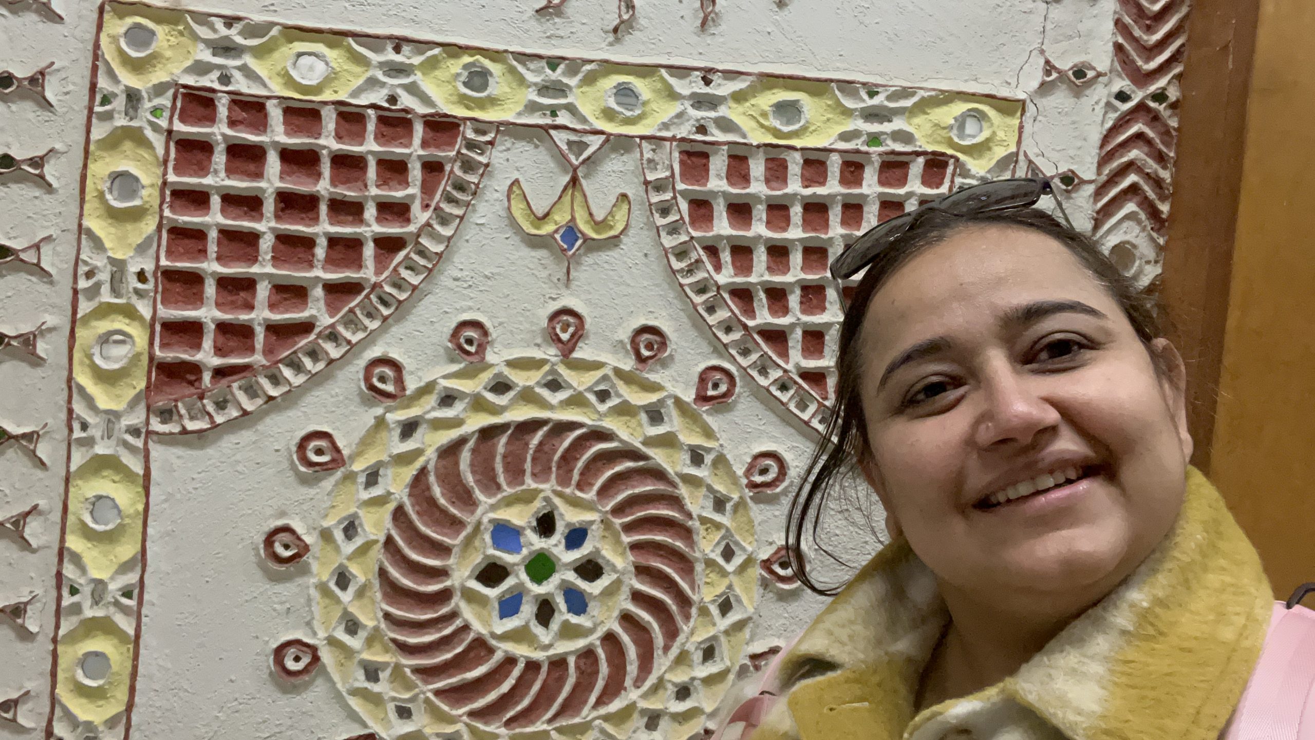 A cheerful moment beside a decorative Kutch craft panel